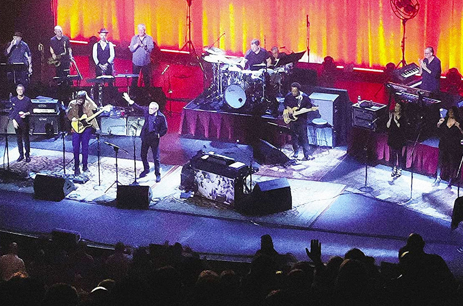 Photo of the cover from the Steely Dan New Live Album and Limited Edition Vinyl. The image features a photo of the band playing on a black stage in front of orange curtains.
