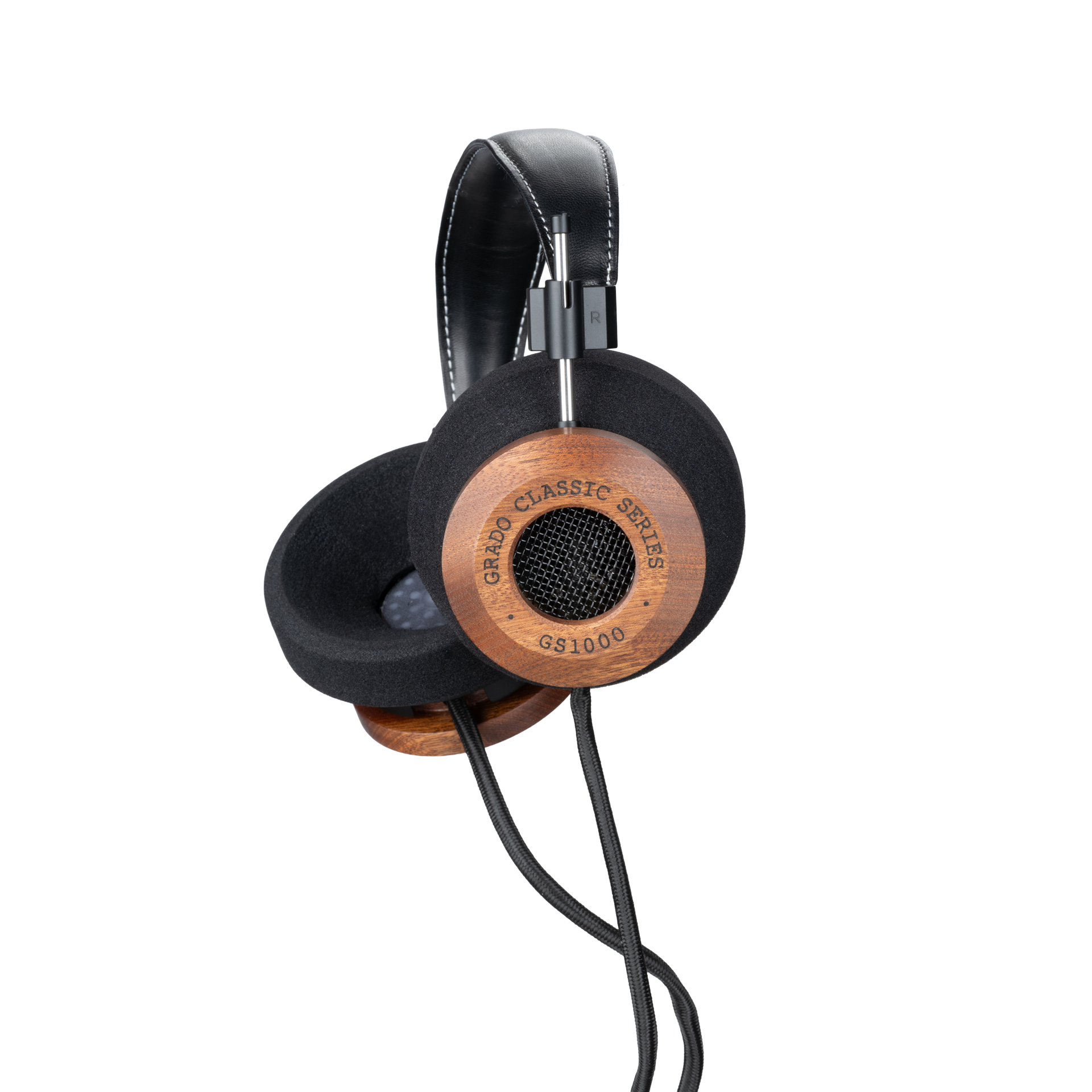 Photo of Grado GS1000 Headphones on a white background taken from the 3/4 view - One ear cup is facing down while the other ear cup is facing outward - the words - Grado Classic Series - and - GS1000 - can be seen on the ear cup.
