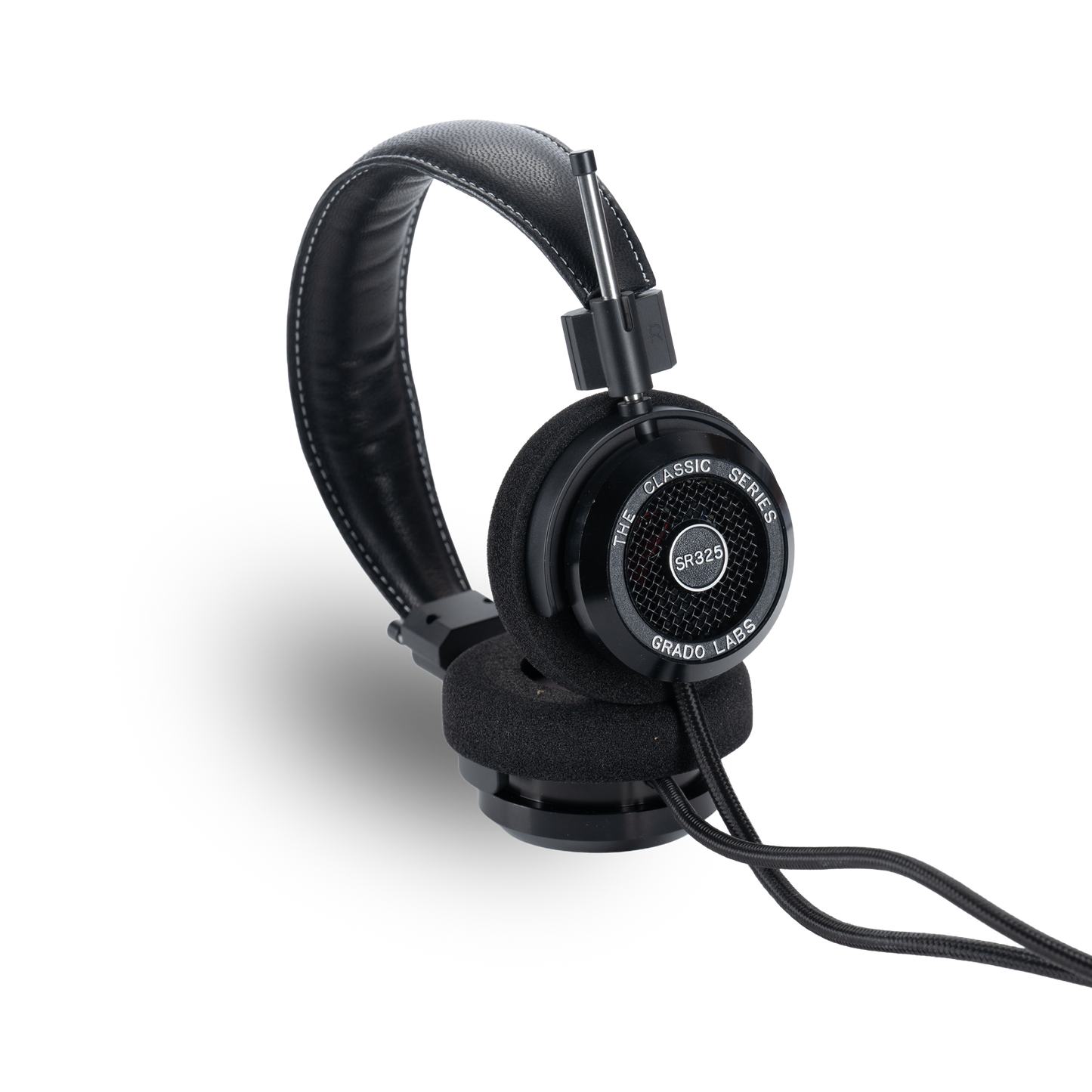 Photo of Grado SR325 Headphones taken from the 3/4 view - One ear cup is facing down while the other ear cup is facing outward - showing the model name in the center - SR325 - and the words - The Classic Series - and - Grado Labs - written along the edge of the ear cups.