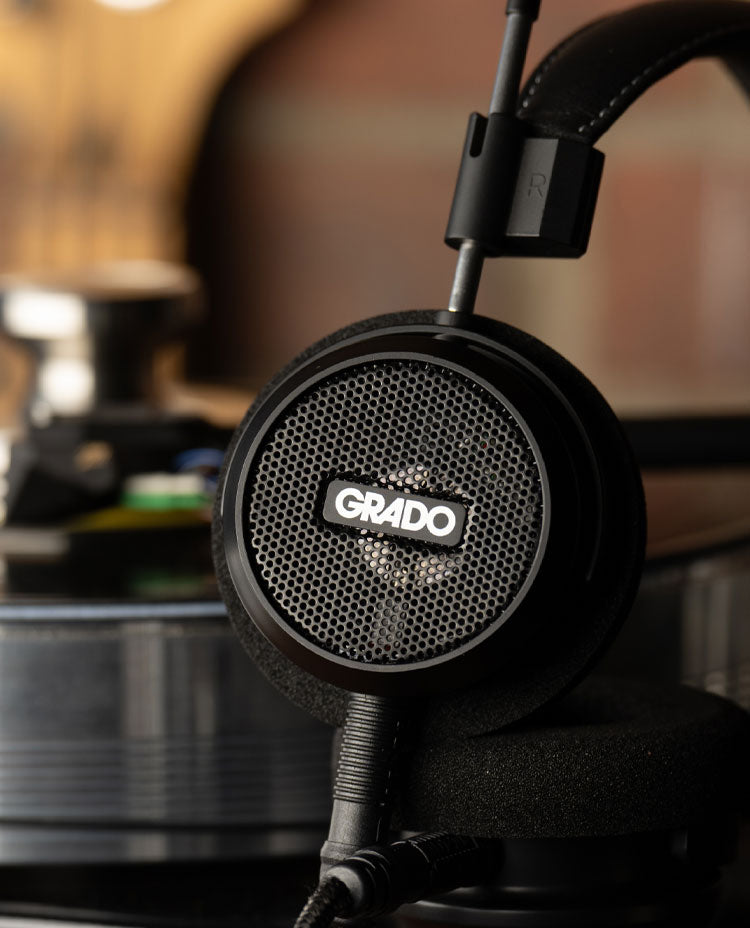 Photo of the S150 Headphones resting next to a turntable in front of a red brick wall.